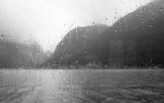 A rainy window overlooking a stormy landscape, symbolizing emotional reflection and resilience during challenging times.