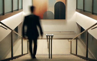 Reflective image of a person in a business suit ascending a building's staircase, symbolizing progress, personal growth, and the journey toward self-improvement and mental well-being.
