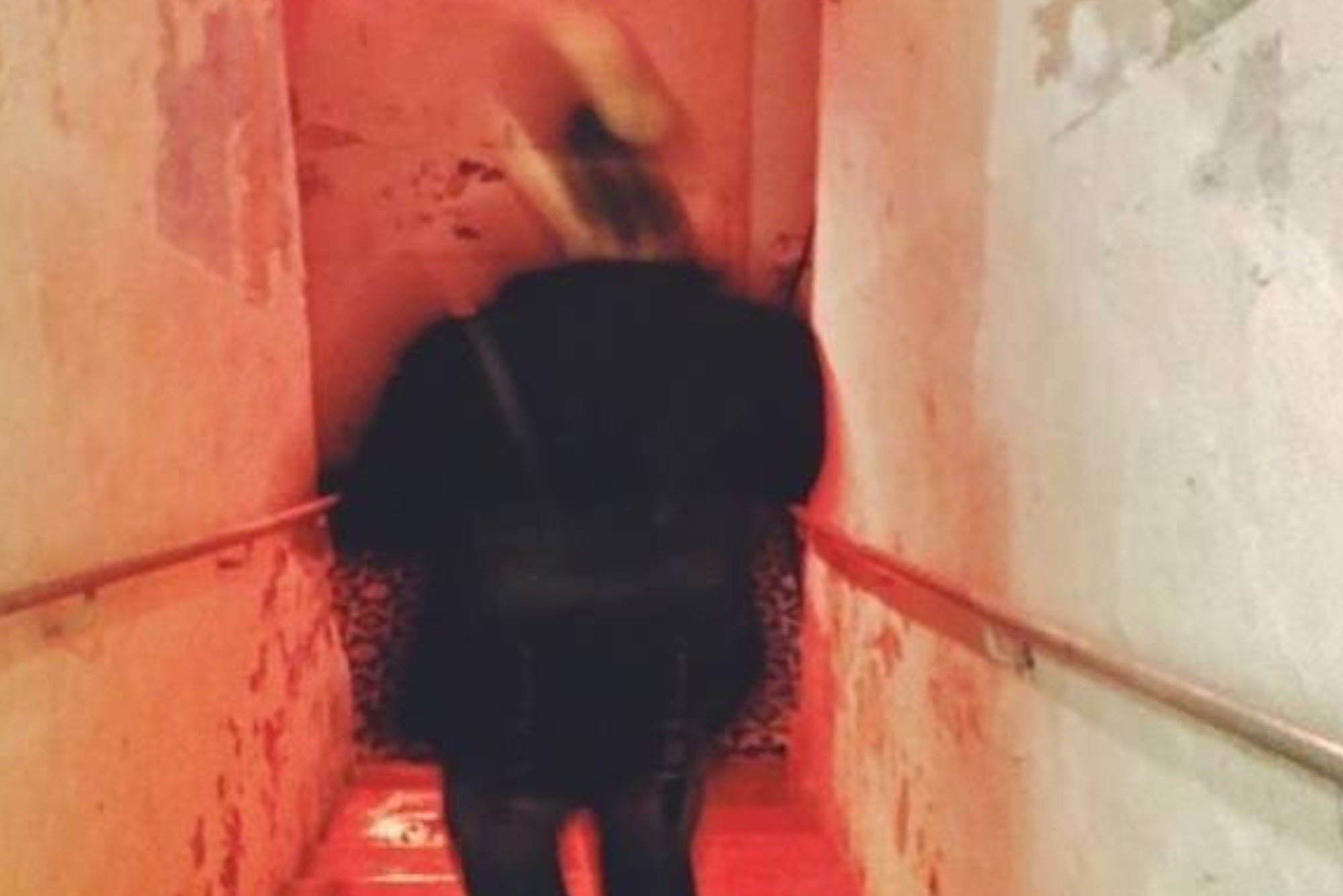 Matthew going down a staircase. Photo shows movement and is blurry with red light in the background.