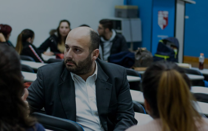 Matthew Bartolo in a lecture room hall with a serious facial expression.