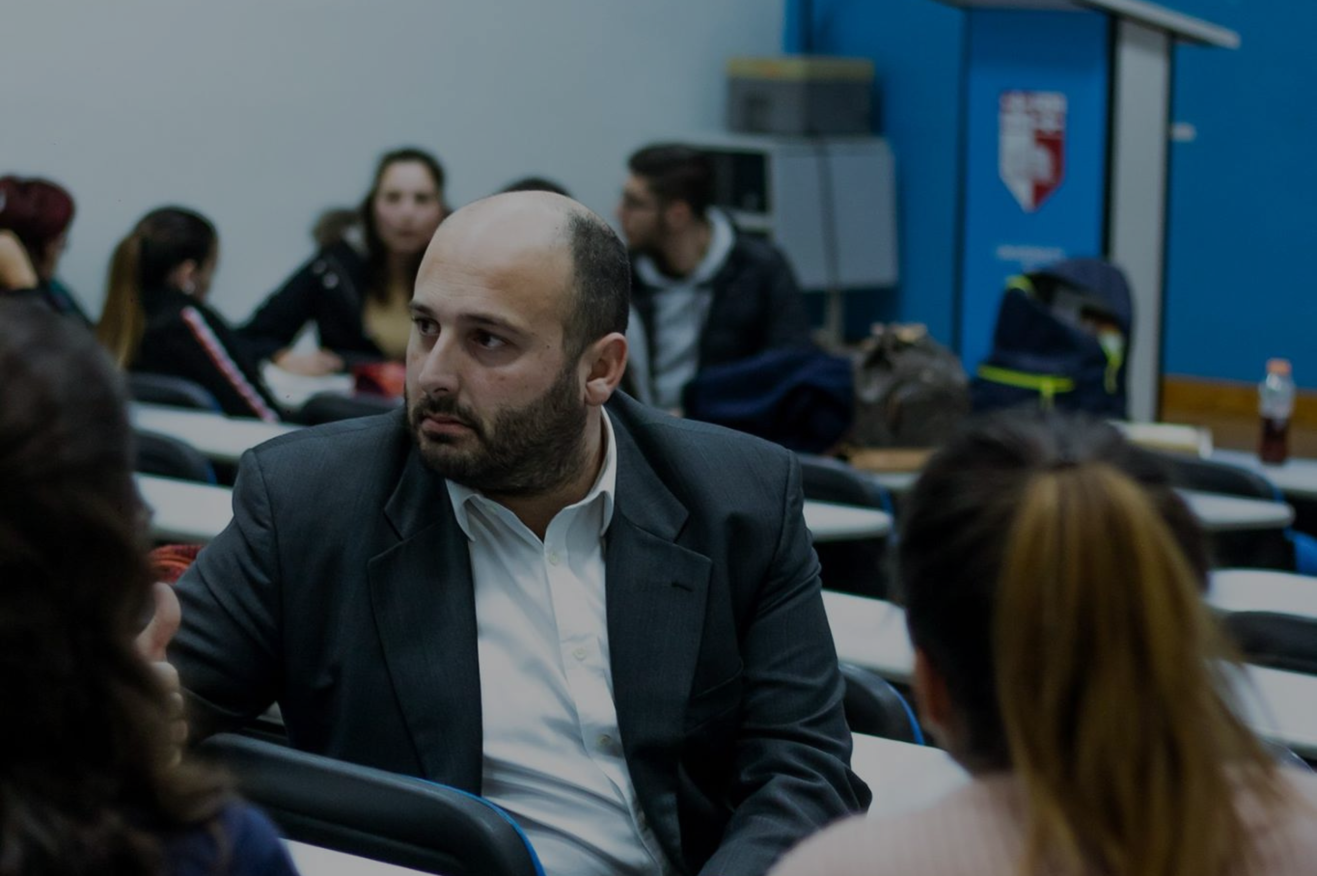 Matthew Bartolo in a lecture room hall with a serious facial expression.