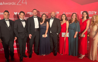 Smiling group of well-dressed individuals posing at a formal event on a red carpet for an awards ceremony.