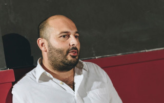 Man speaking in a therapy or counseling session in a clinical setting, focusing on mental health and emotional support, with a serious expression and attentive posture.