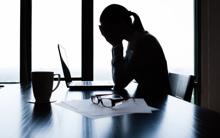 Exhausted leader leaning on desk, reflecting stress and burnout in leadership roles.