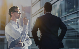 Thinking professionals engaging in deep discussion outside a modern office building, emphasizing focus, collaboration, and strategic planning for business success.